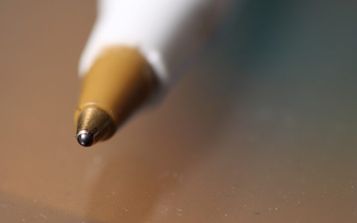 Close-up of the metal tip and ink ball of a ballpoint pen.